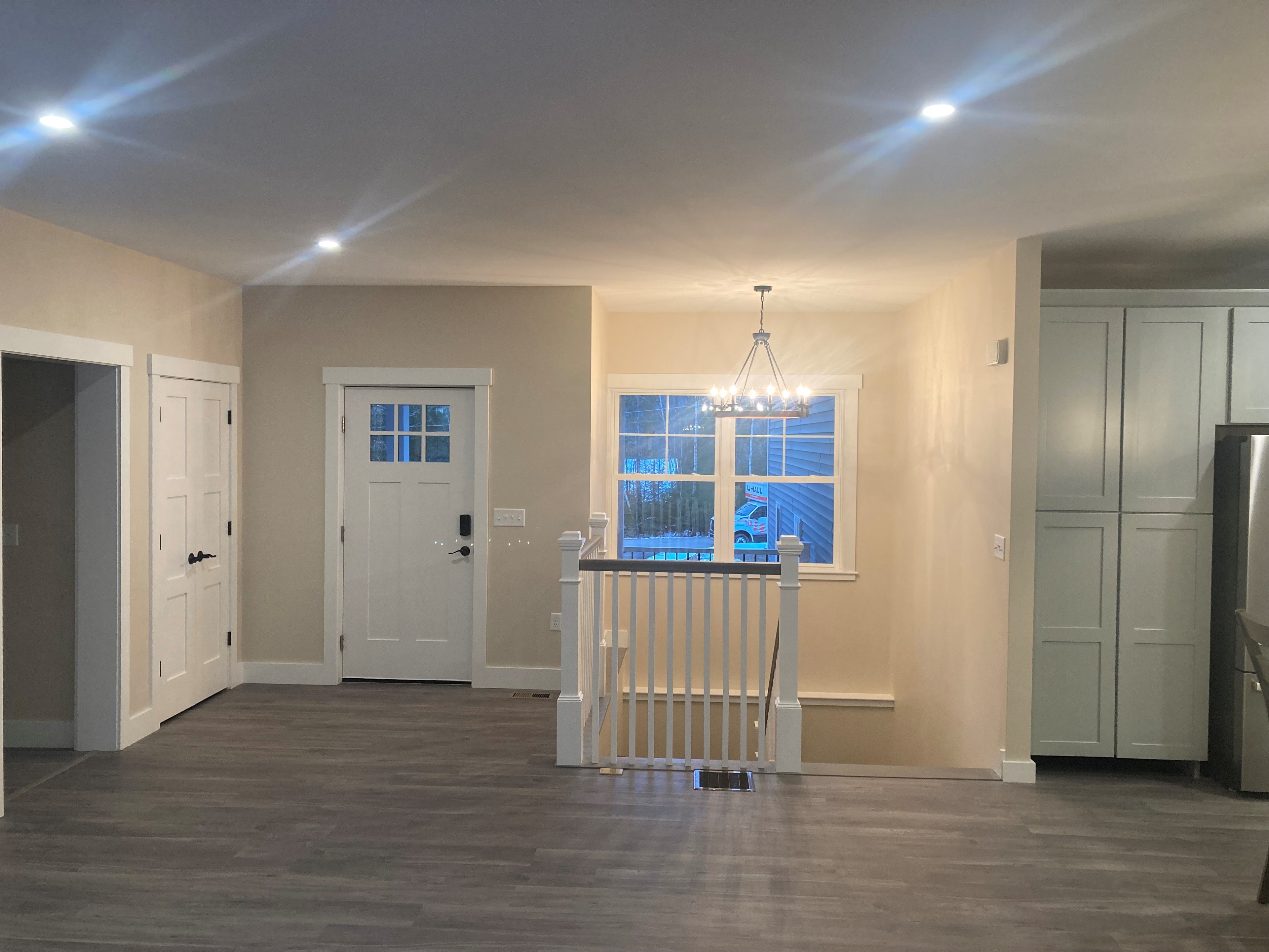 Applewood Estates Home main level open plan with craftsman front door, stair railing, chandelier, and sage green cabinetry