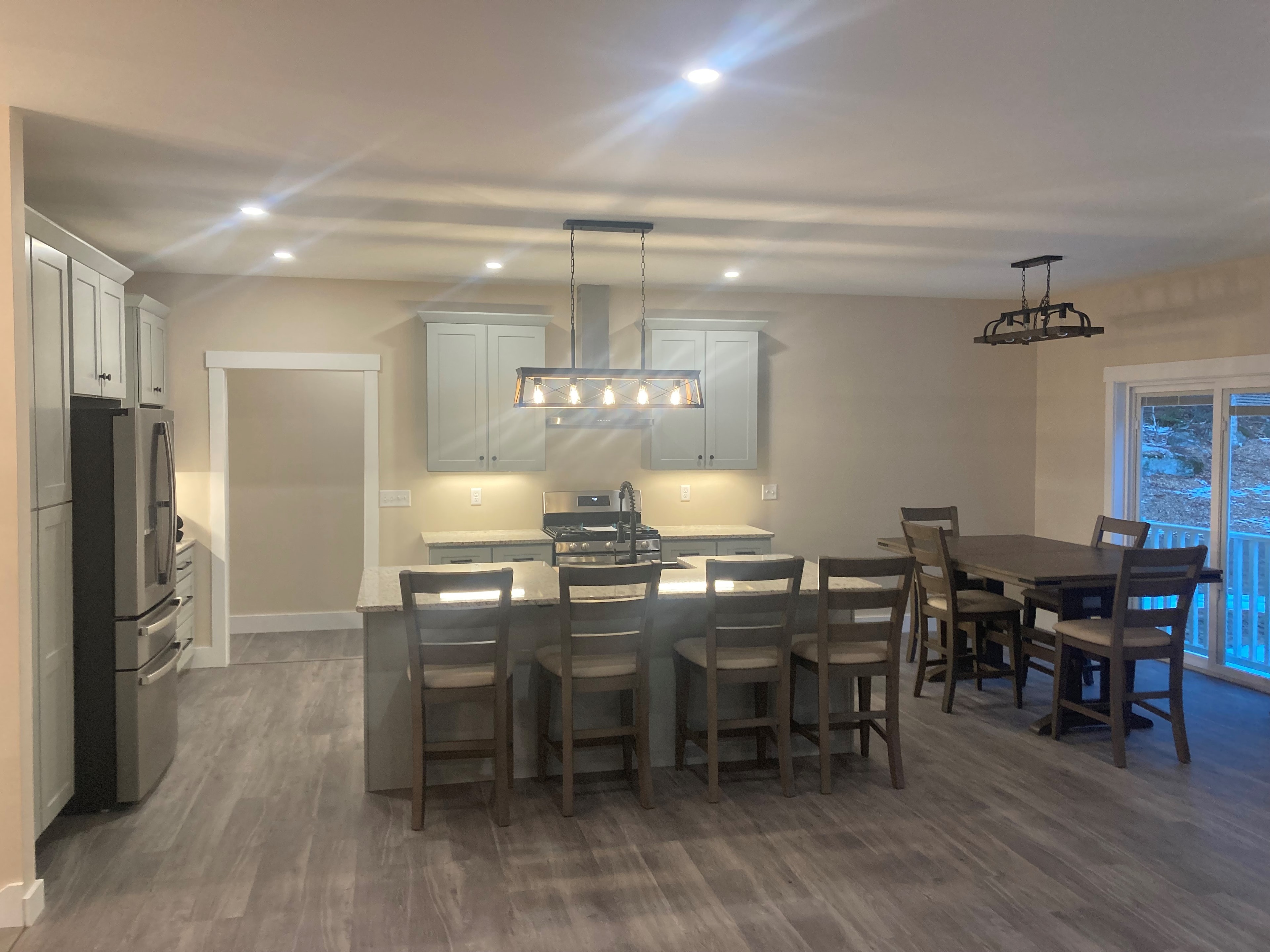 Applewood Estates Home kitchen with sage green shaker cabinets, granite island with bar seating, stainless range hood, and dining area