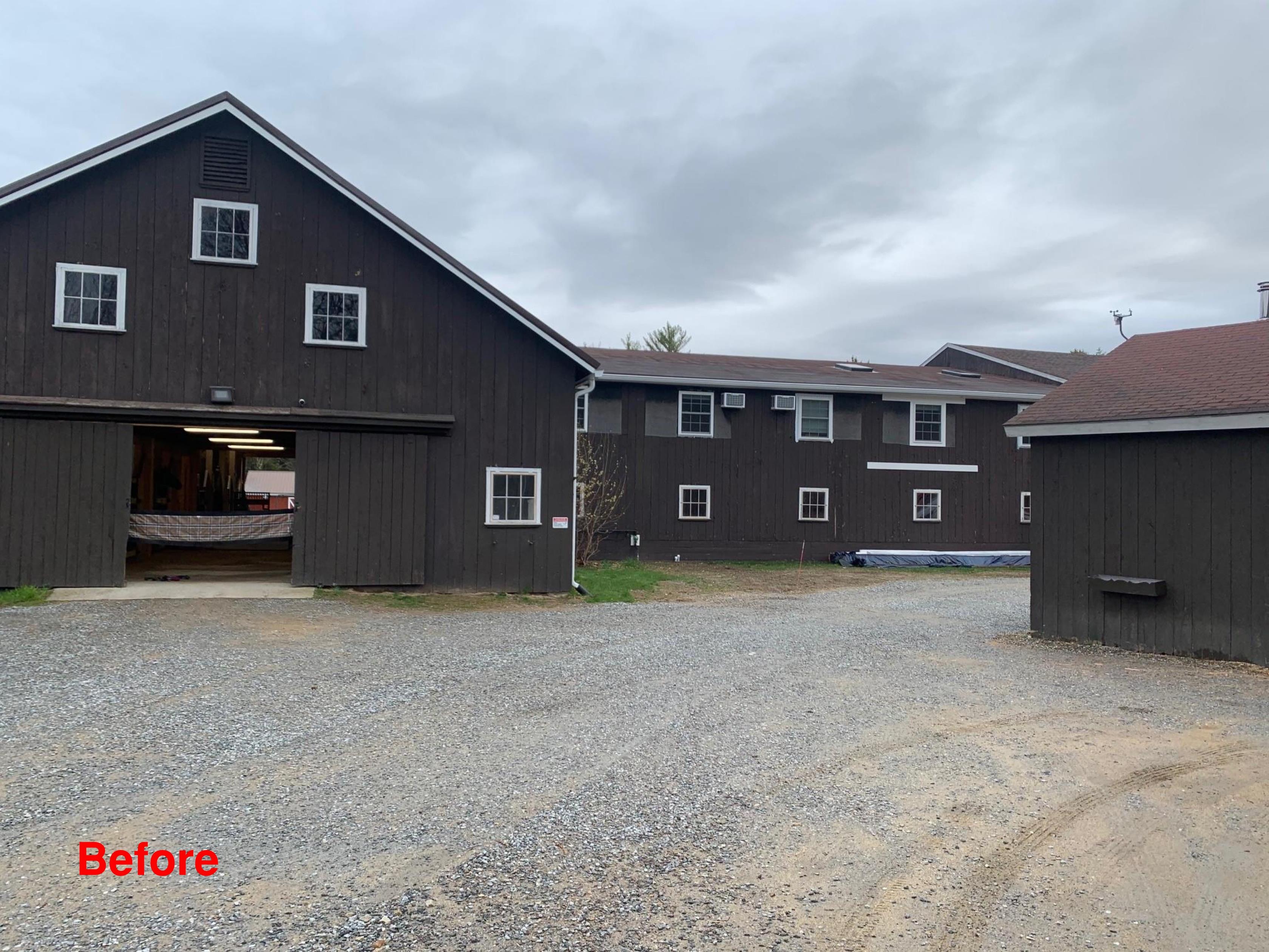 Century Farm Renovations before exterior — original dark brown board-and-batten barn complex with white-trimmed windows and gravel drive — Belmont, NH