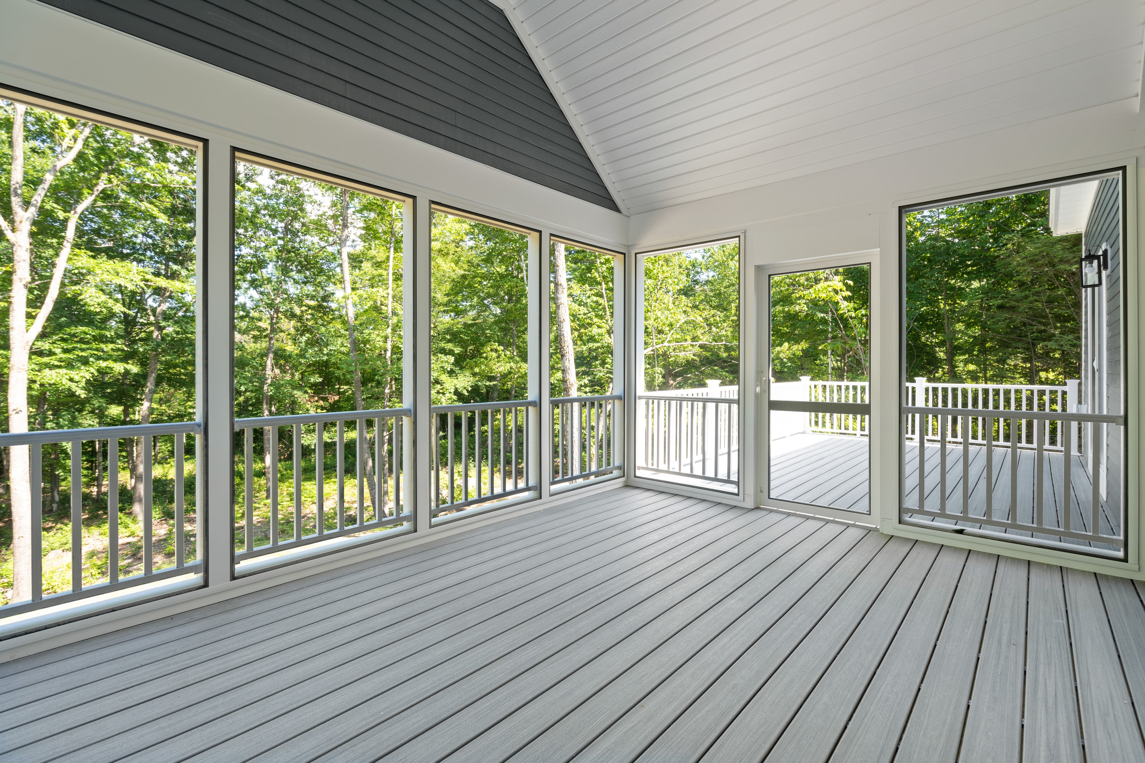 Clover Ridge Home screened porch with vaulted beadboard ceiling, composite deck, and panoramic wooded views — Meredith, NH