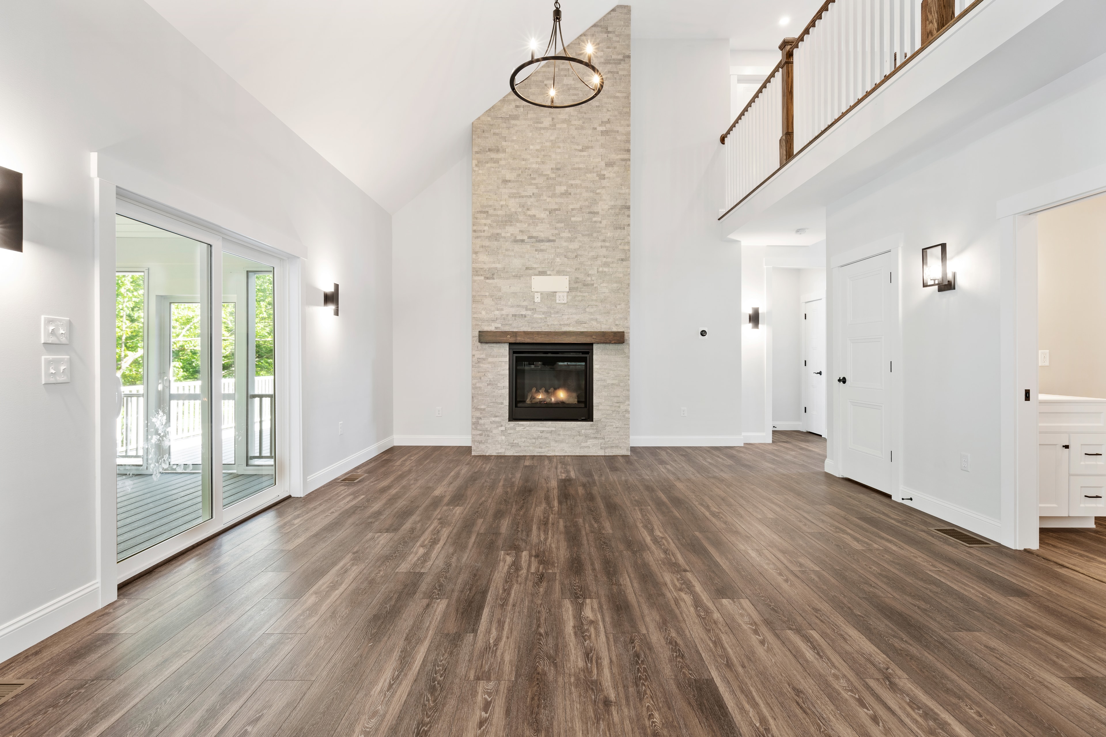 Clover Ridge Home great room with vaulted ceiling, floor-to-ceiling stacked stone fireplace, wood mantel, and open staircase — Meredith, NH