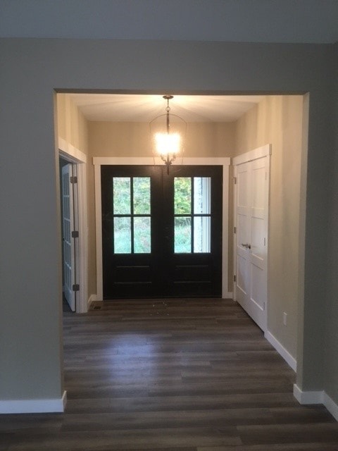 Custom New Build entry foyer with black double French doors, pendant chandelier, and wide-plank hardwood floors — Bedford, NH