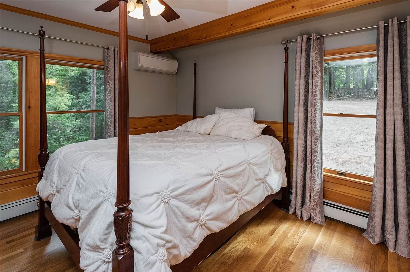 Dew Duck House finished lower level with drop ceiling, round dining table, sectional sofa, wall-mounted TV, and staircase — Meredith, NH