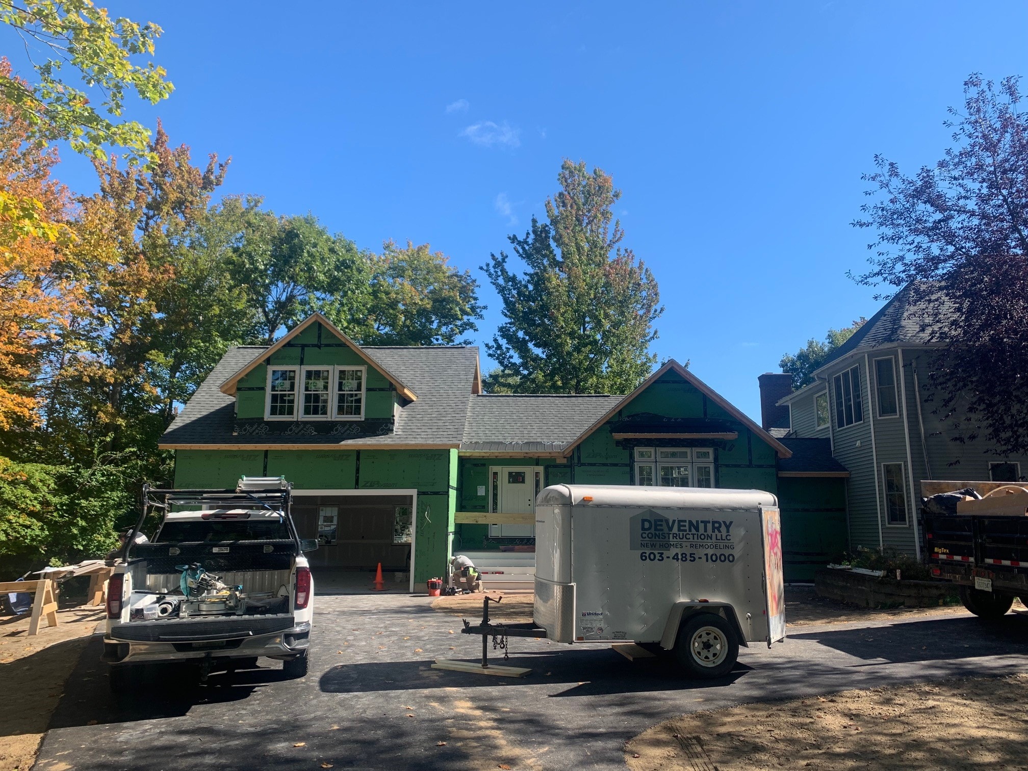 Garage Addition under construction showing green house wrap, framing, and Deventry Construction trailer on site — Gilford, NH