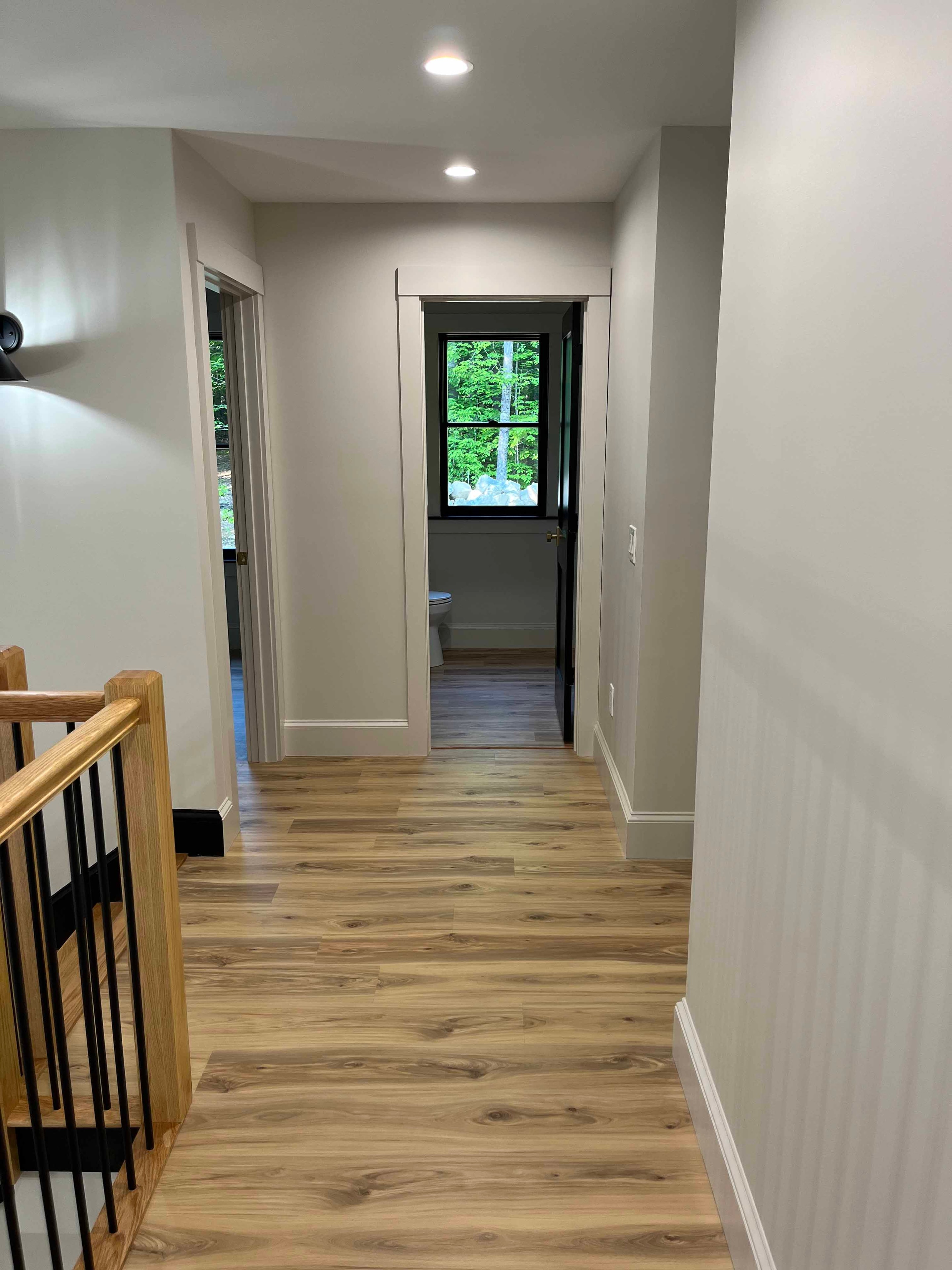 Holderness Home upper hallway with oak railing, black balusters, and black-framed window