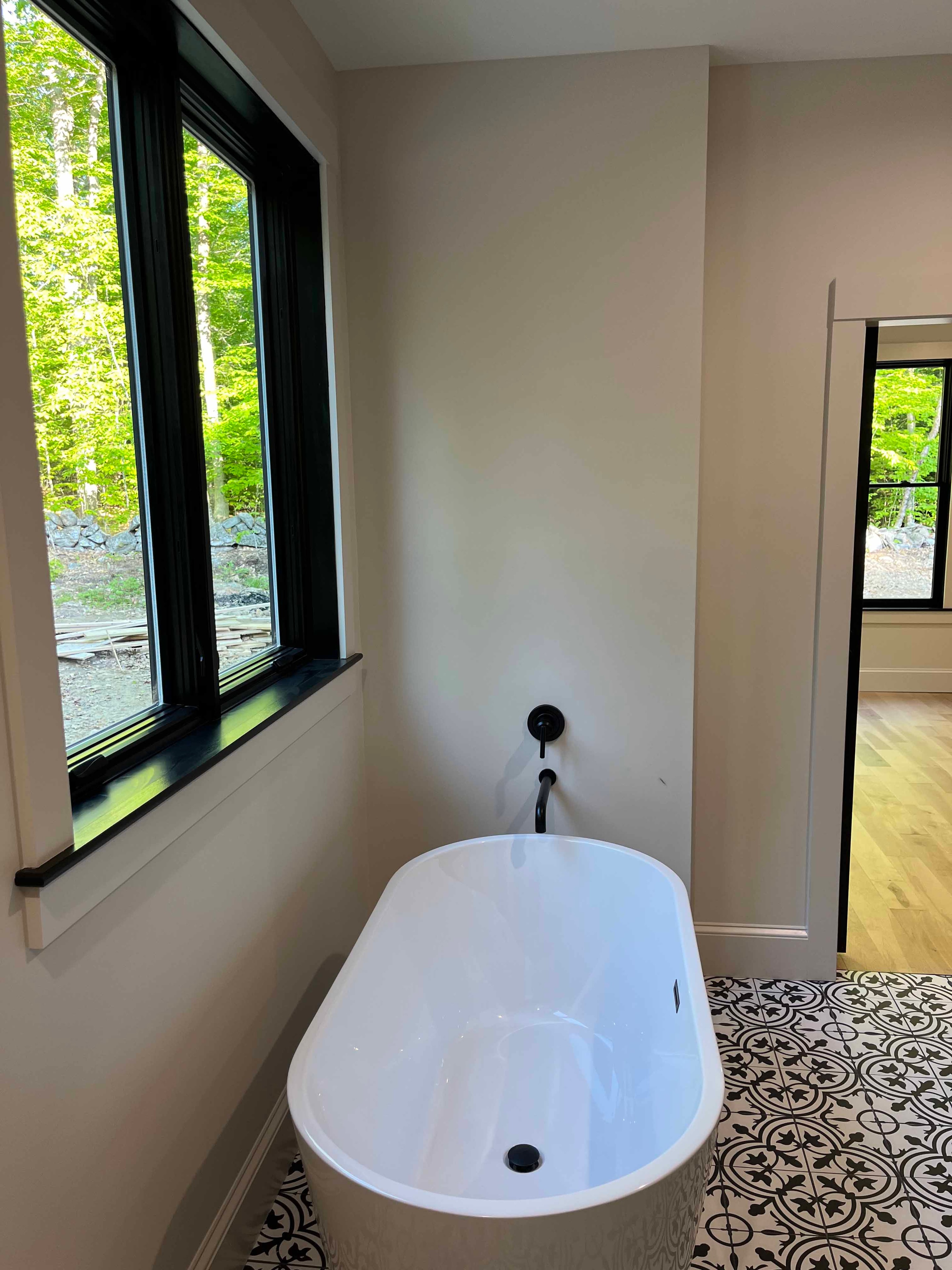 Holderness Home master bath with freestanding soaking tub, black-framed windows, and patterned tile floor