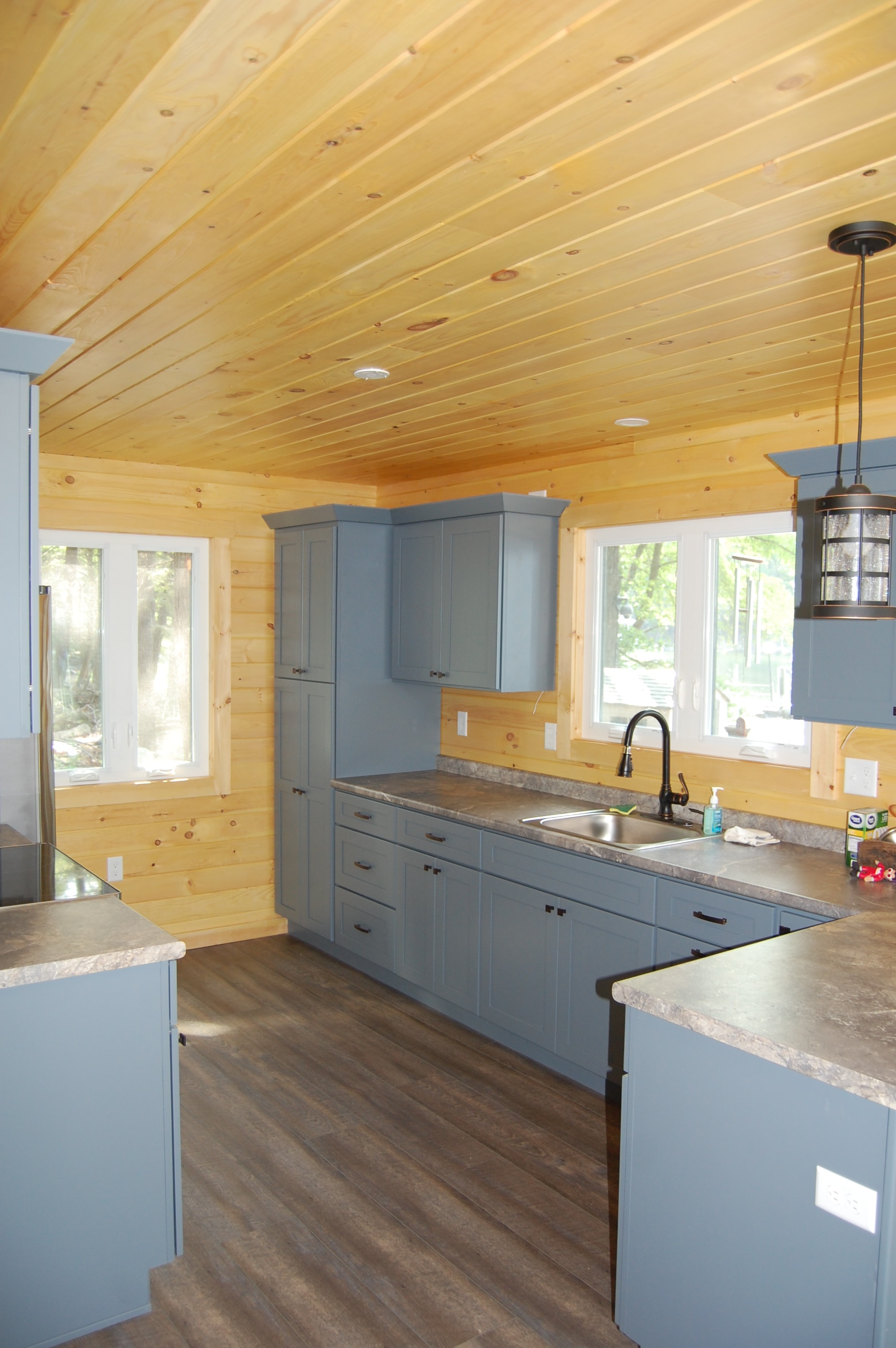 Island Retreat overhead view of gray-blue kitchen with granite countertops, farmhouse sink, pendant light, and dark LVP flooring — Welch Island, Laconia, NH