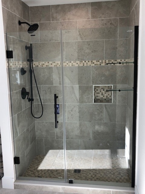 Lake Kanasatka Home walk-in shower with large-format gray tile, mosaic accent band, matte black fixtures, and frameless glass door — Moultonborough, NH