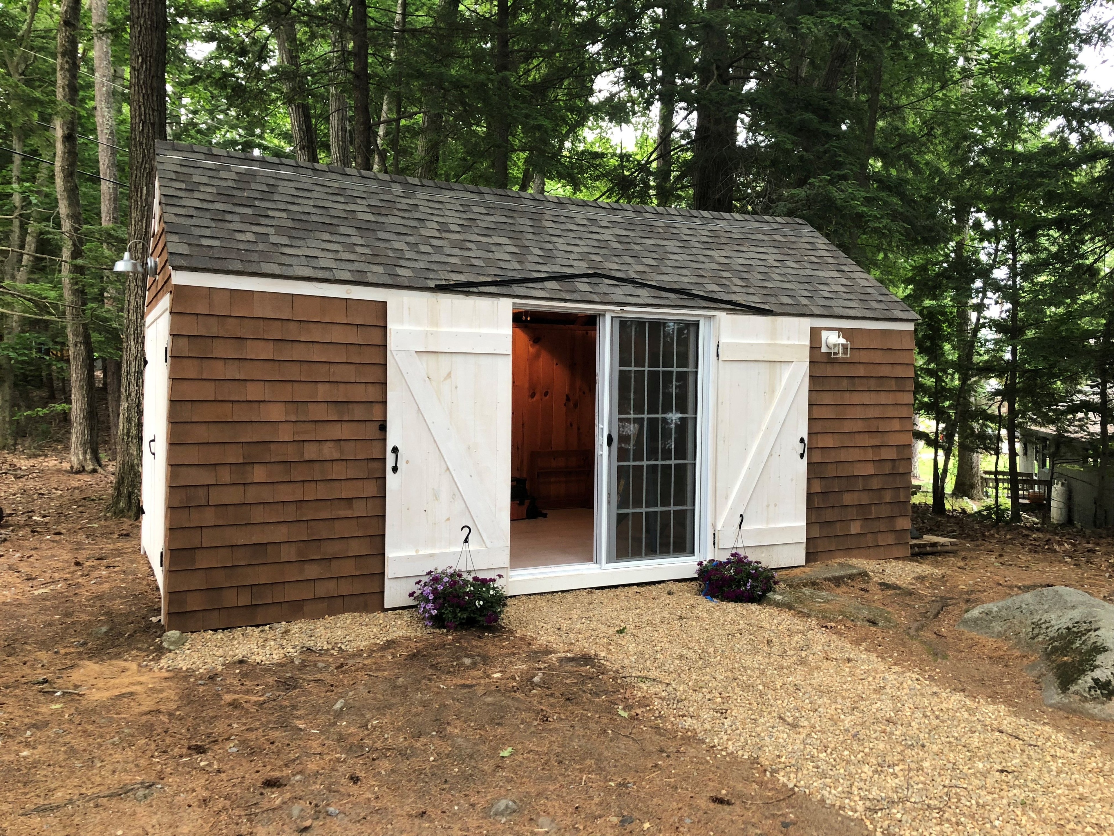 Loon Song Cottage new cedar shake guest house with white barn doors, sliding glass door, and flower boxes — Meredith, NH