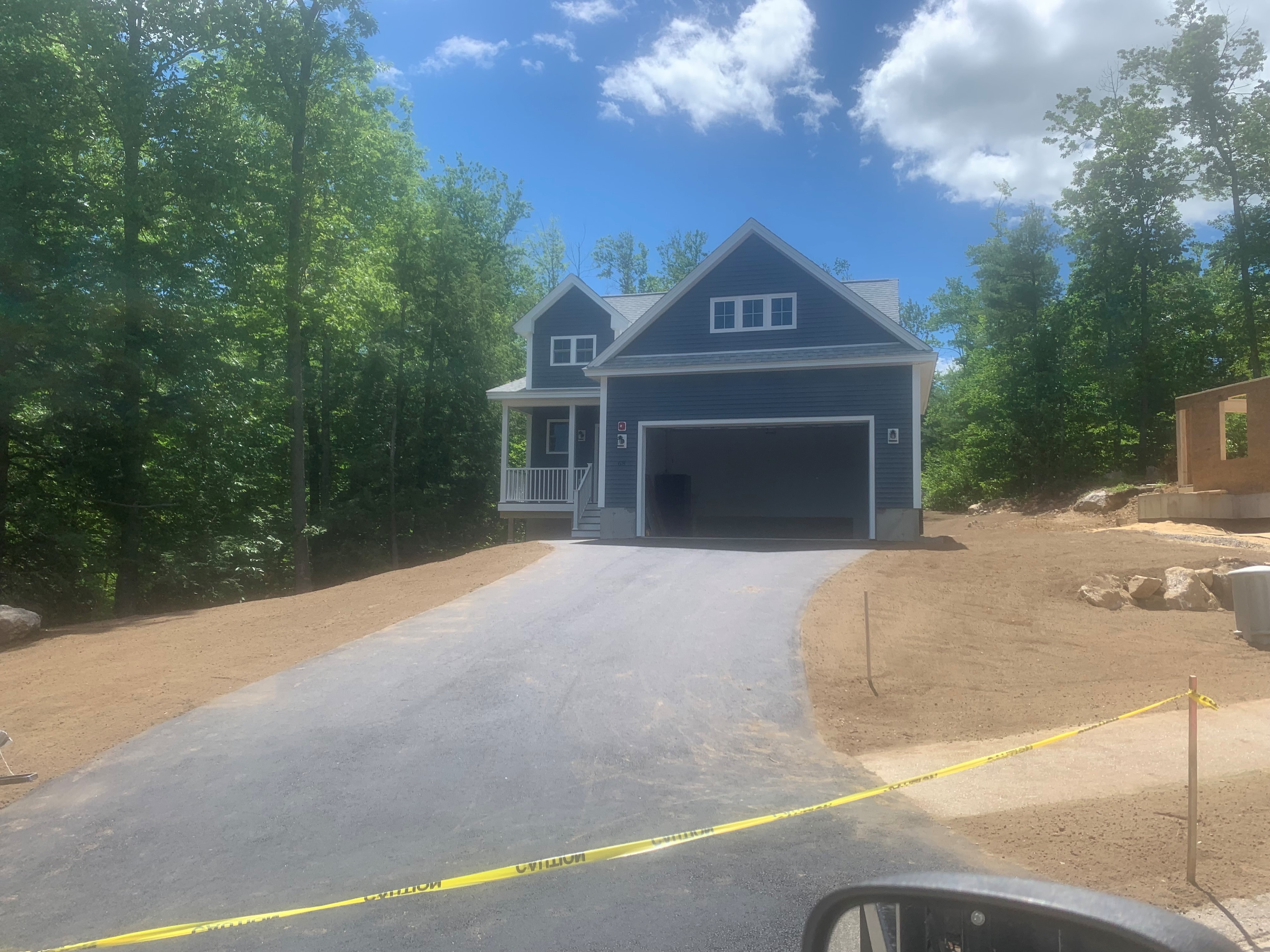 Mason New Build blue two-story exterior with white trim, covered porch, two-car garage, and new asphalt driveway surrounded by summer trees — Governor's Crossing, NH