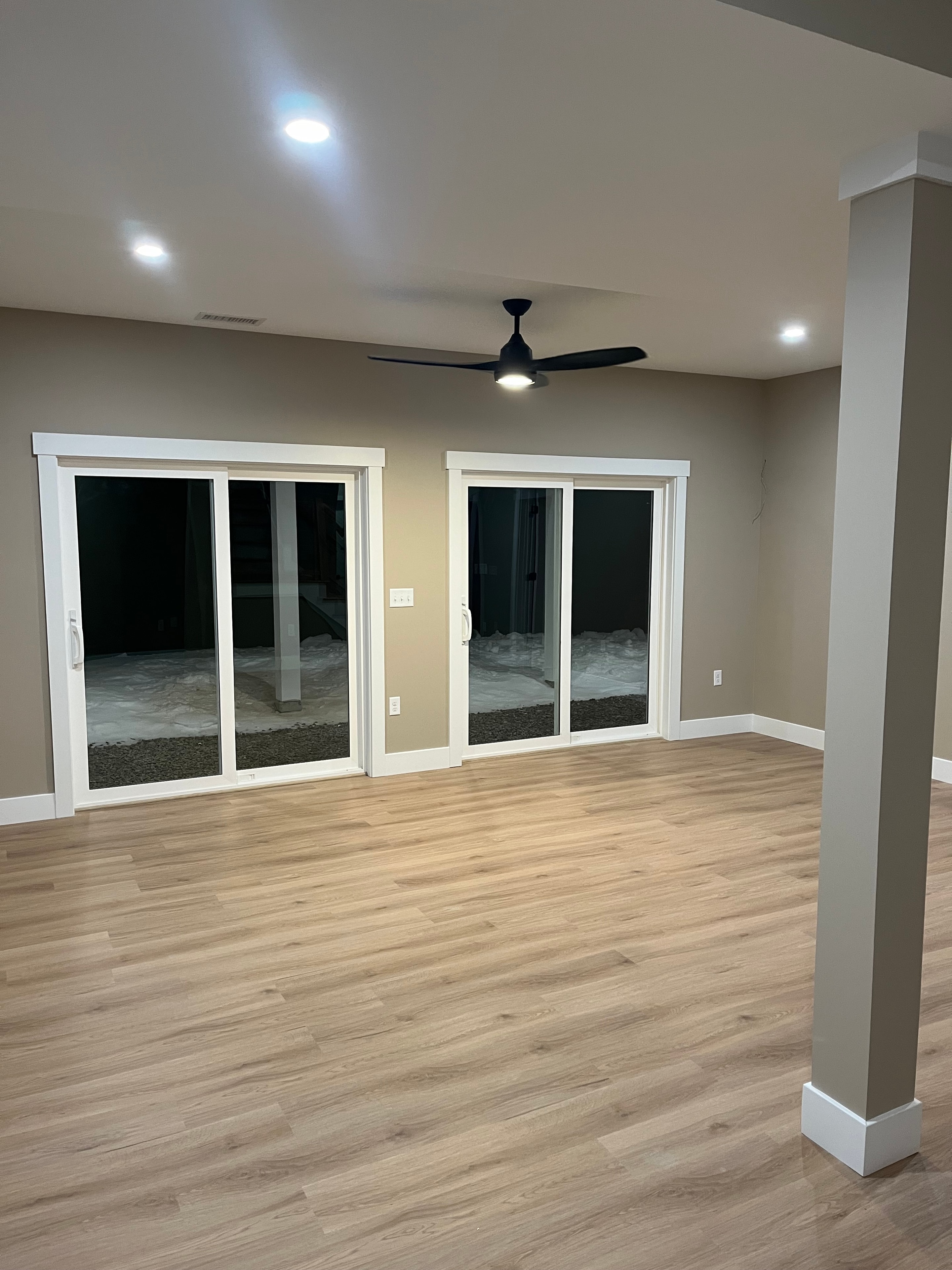 Mountain View Home bedroom with taupe walls, white trim, black ceiling fan, double windows, and light oak LVP flooring