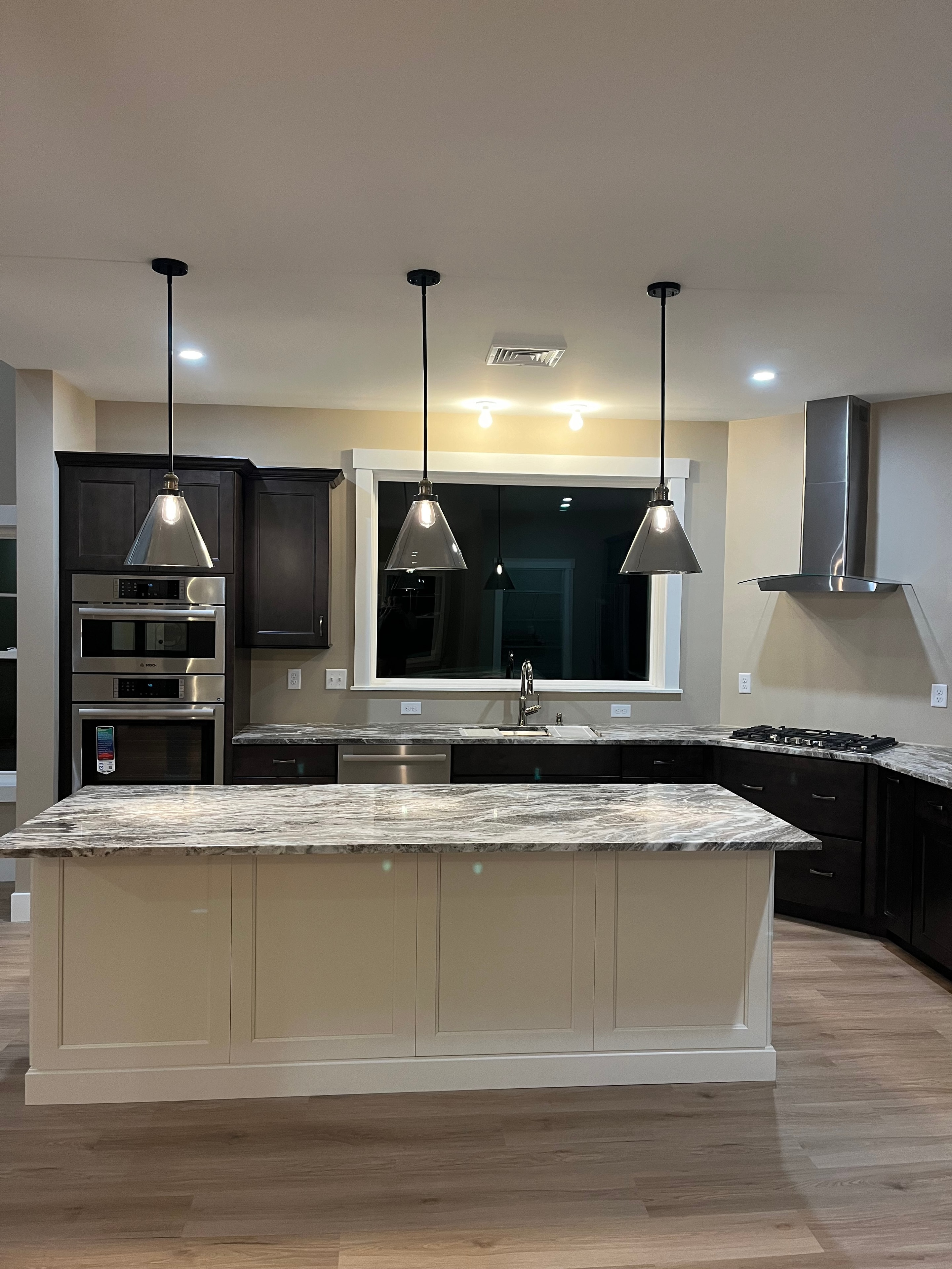 Mountain View Home kitchen with dark espresso cabinets, granite island, stainless appliances, and industrial pendant lights