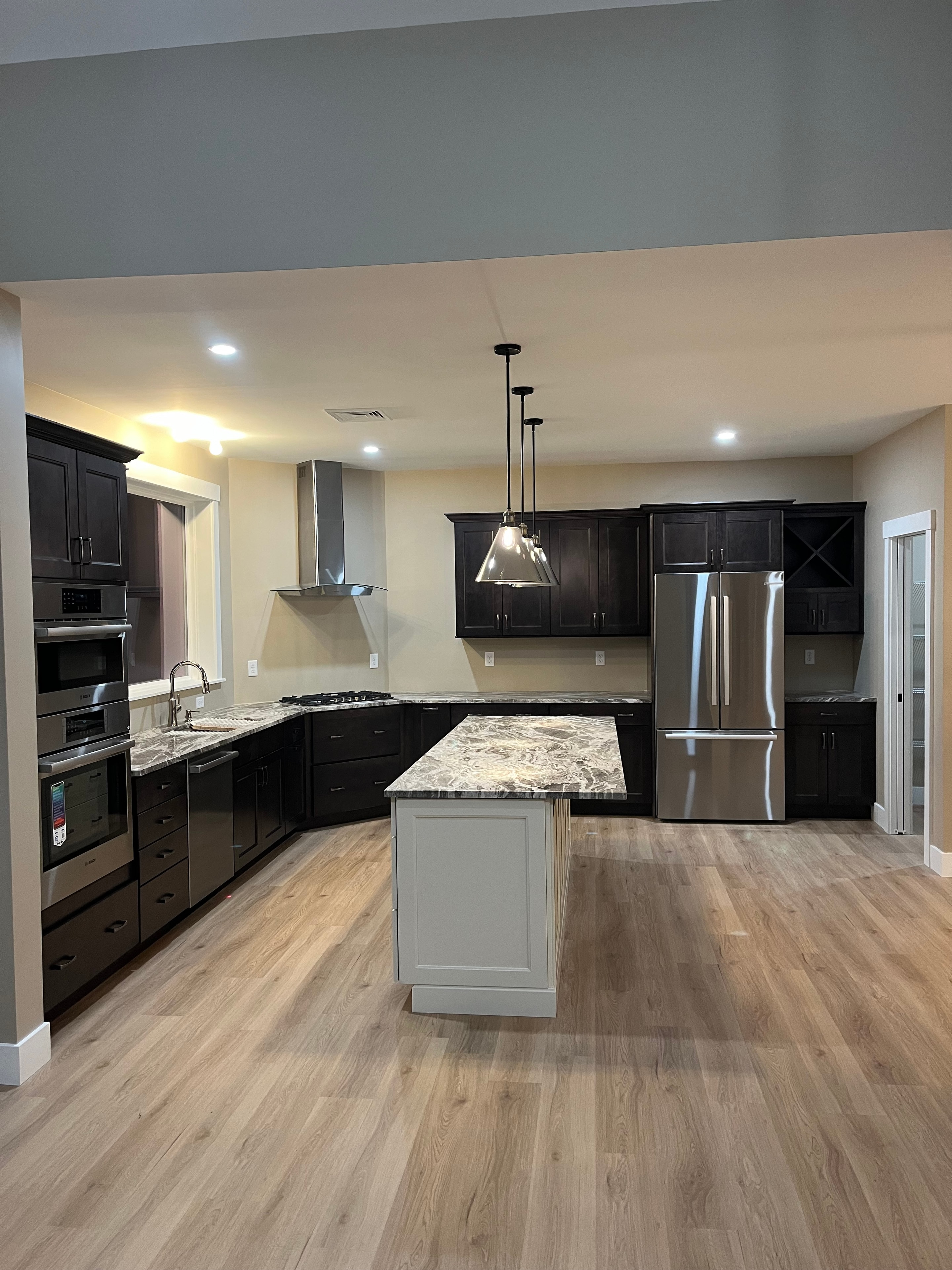 Mountain View Home kitchen wide angle with dark cabinets, stainless refrigerator, granite island, and pendant lights