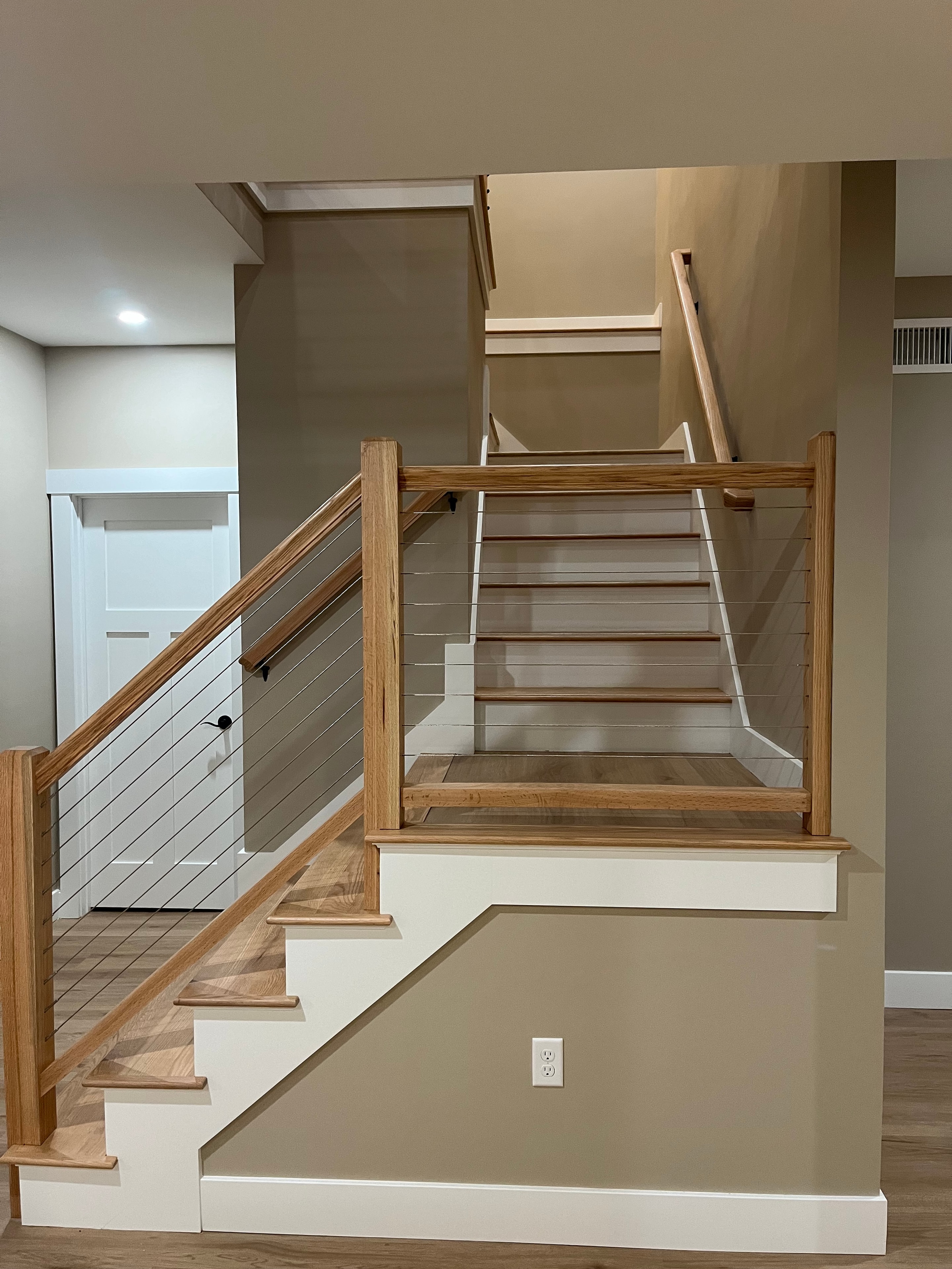 Mountain View Home staircase with oak treads, cable wire railing, and white shaker built-ins below