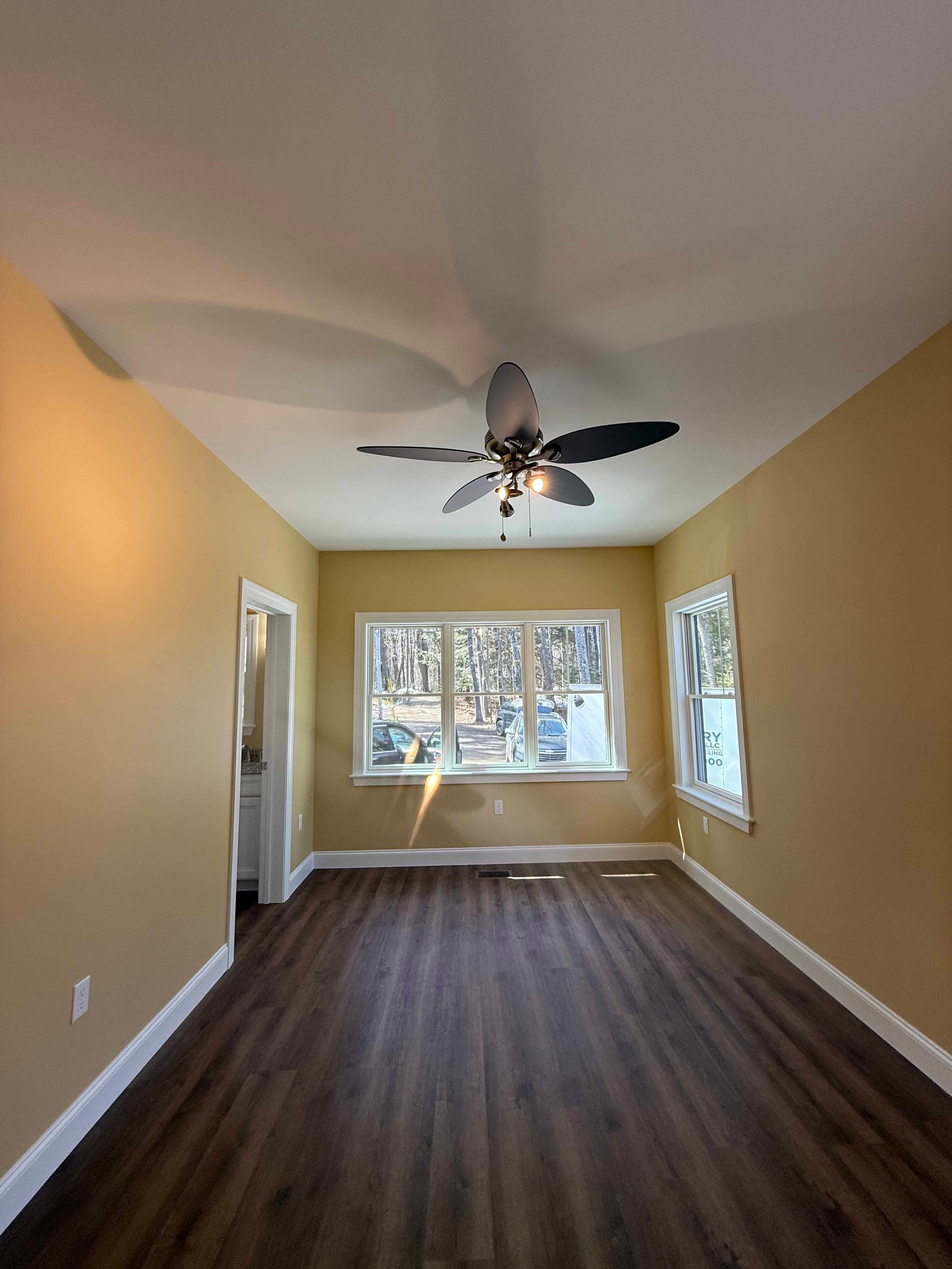 Squam Lake Home stairwell with wood railing, white balusters, and decorative pendant light