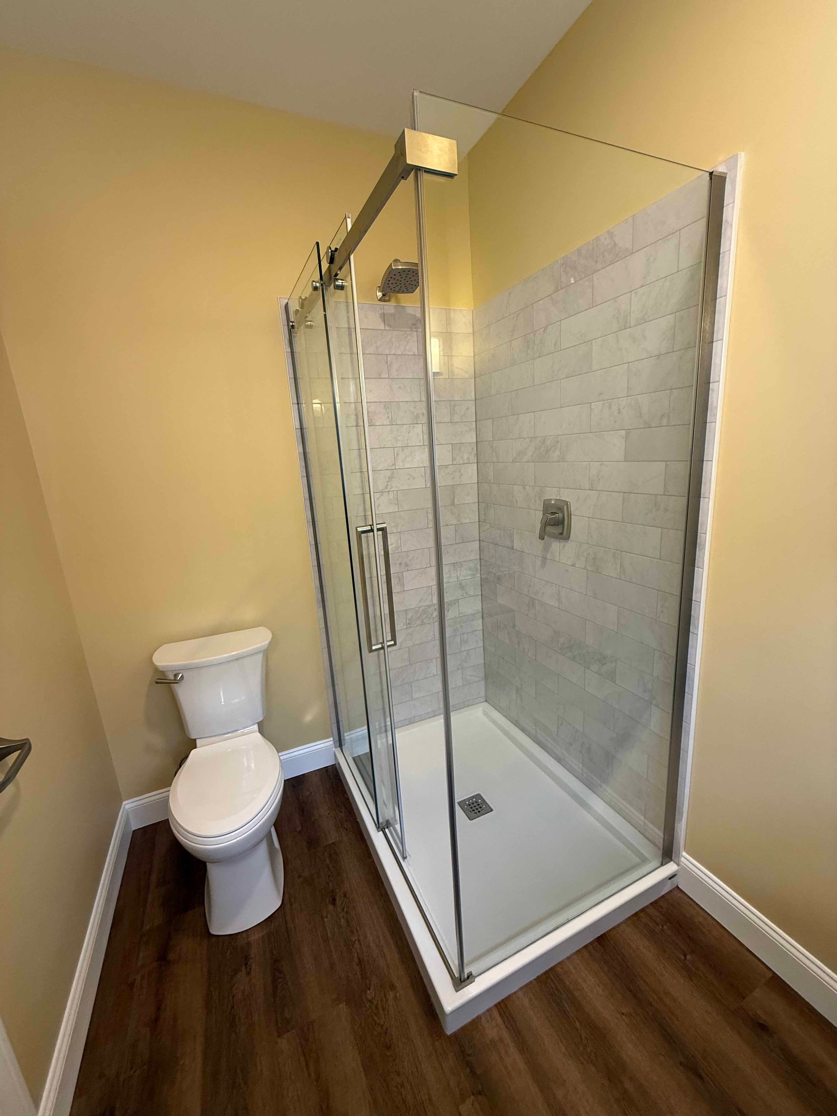 Squam Lake Home bedroom with yellow walls, ceiling fan, and windows overlooking wooded yard