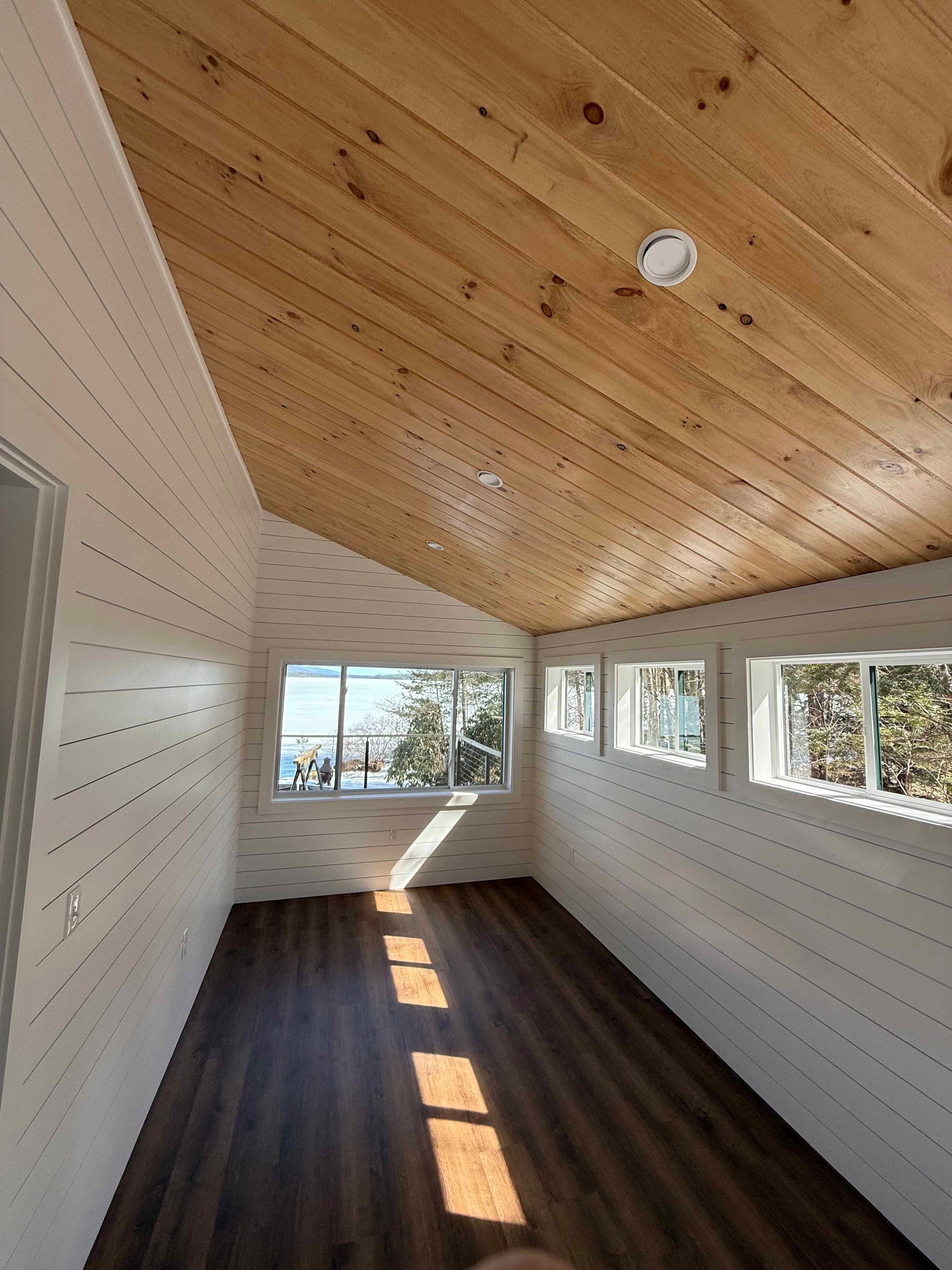 Squam Lake Home bathroom with glass shower enclosure, marble tile, and toilet