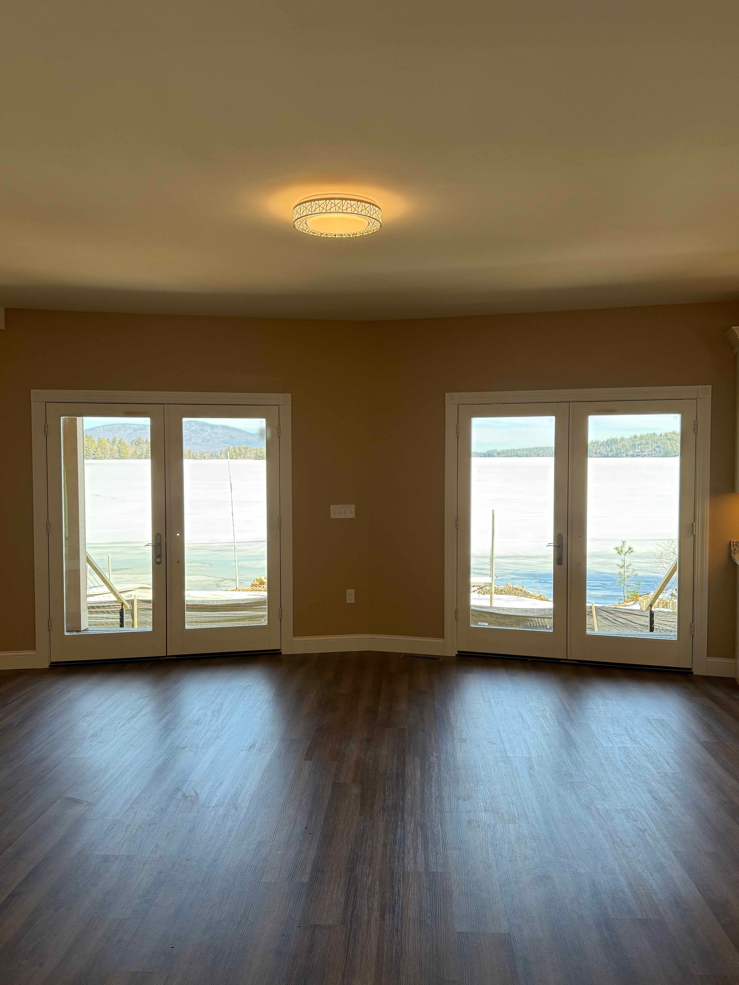 Squam Lake Home sunroom with shiplap walls, pine ceiling, and panoramic lake-view windows