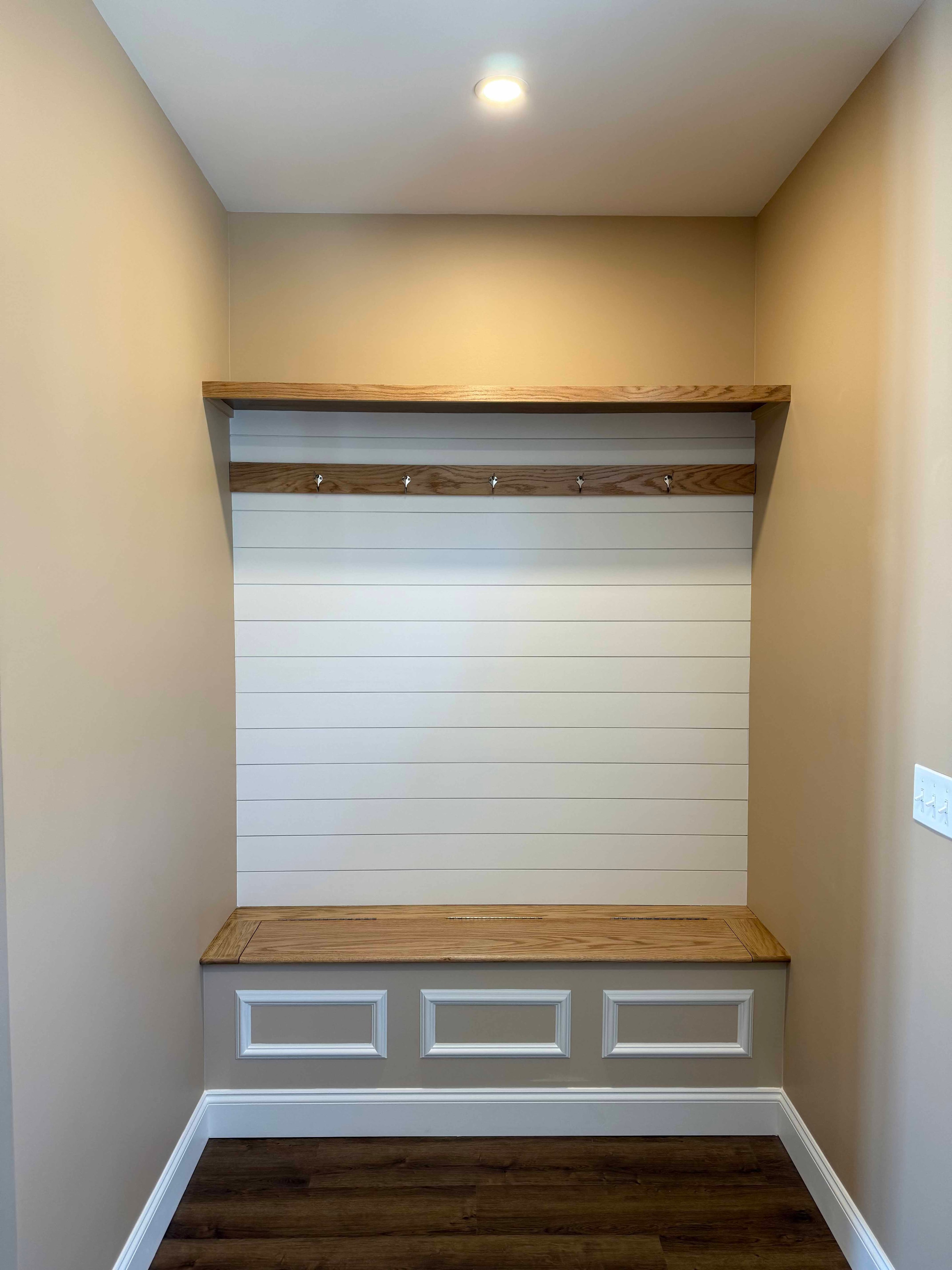 Squam Lake Home mudroom with shiplap wall, oak bench, coat hooks, and wood shelf