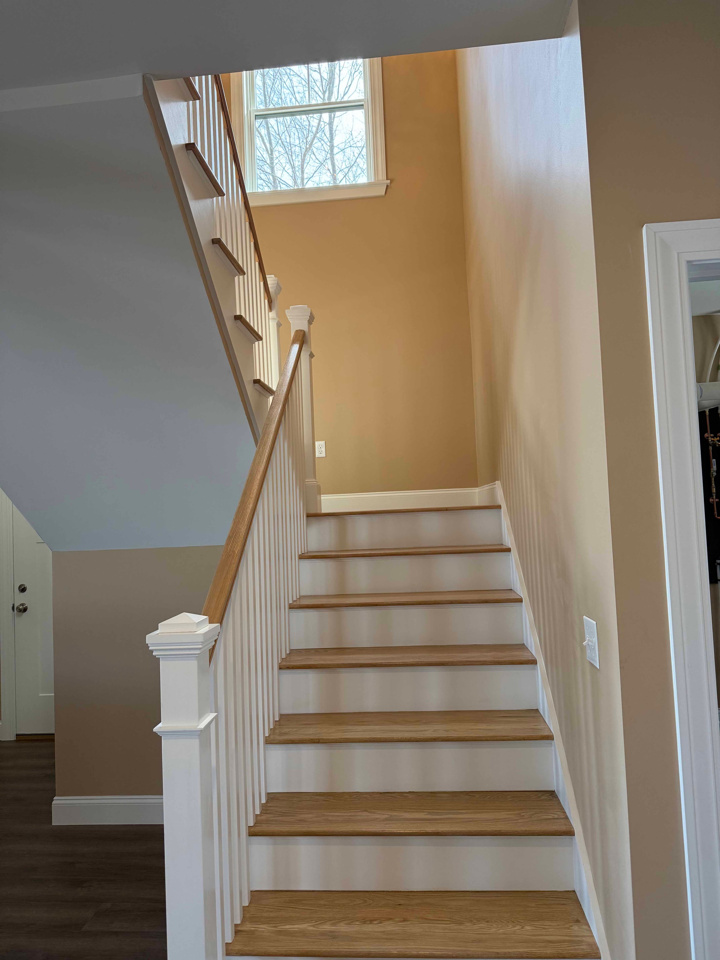 Squam Lake Home open foyer with craftsman front door, staircase, and dark hardwood floors