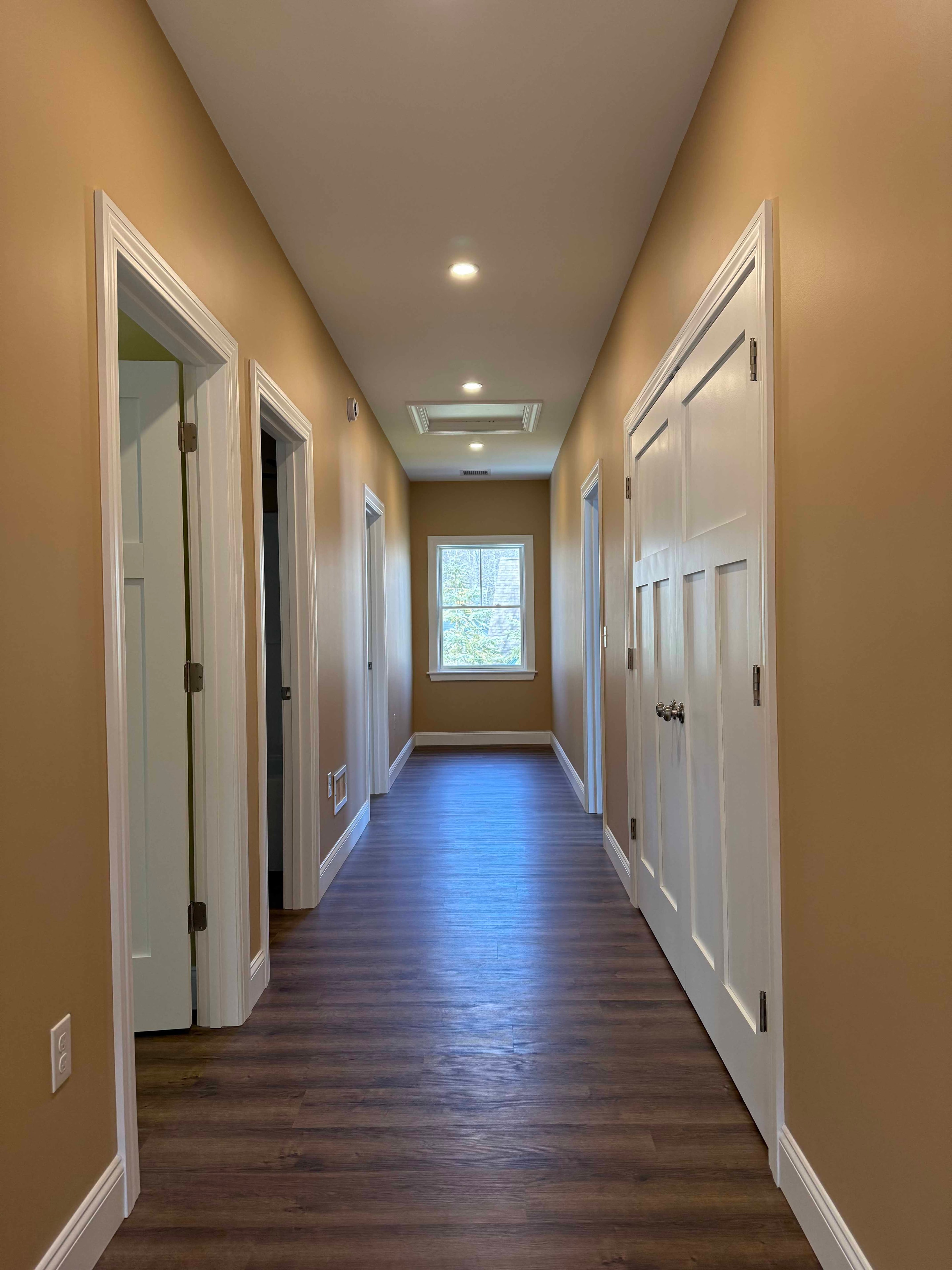 Squam Lake Home staircase with oak treads, white balusters, and window above landing