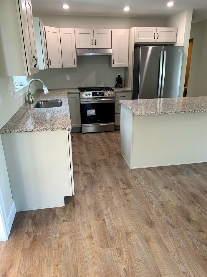 Webster New Build kitchen with white shaker cabinets, granite countertops, stainless appliances, and wide-plank floors — Governor's Crossing, NH