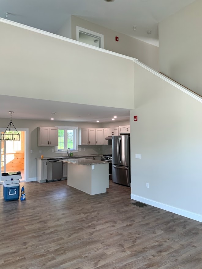 Webster New Build open-concept main living area with two-story staircase, gray shaker kitchen, granite island, and stainless appliances — Governor's Crossing, NH