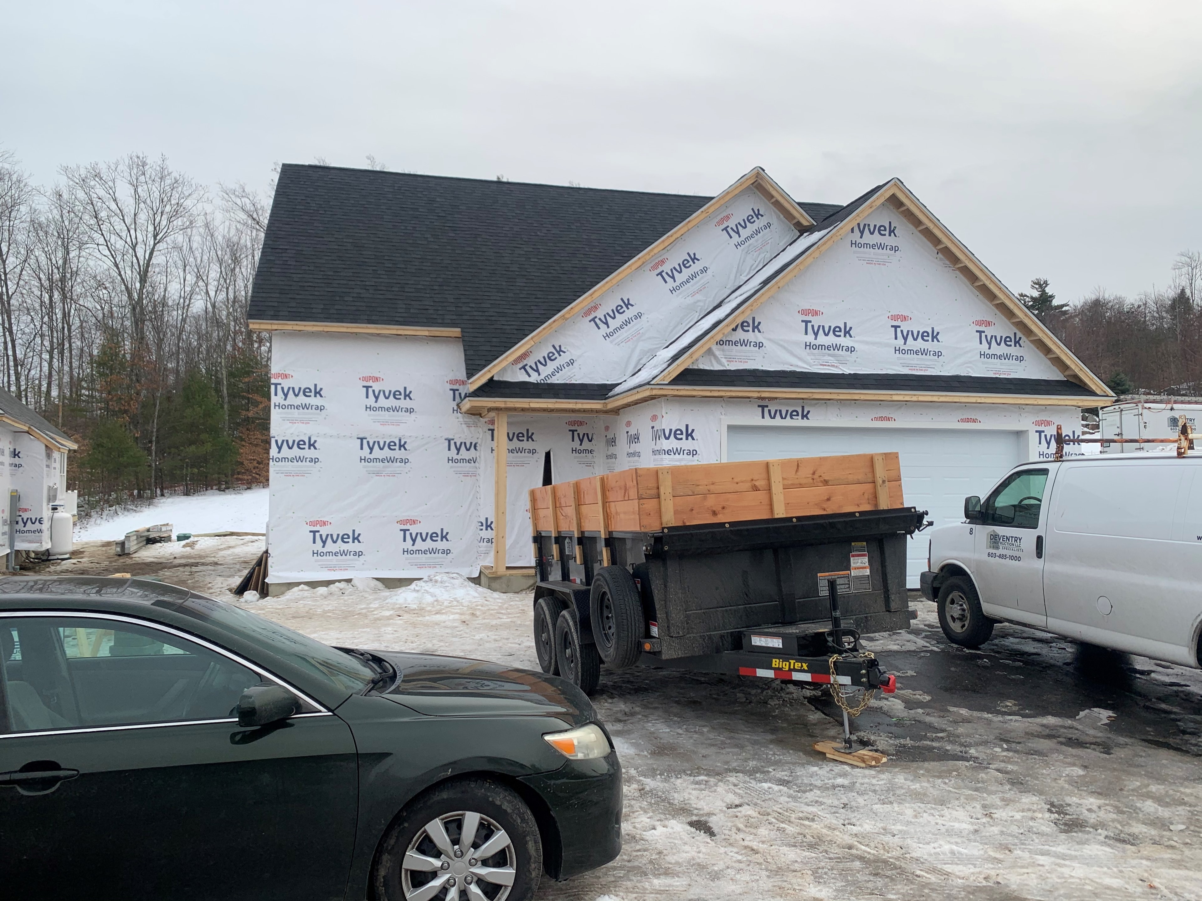 Webster New Build winter framing progress with Tyvek wrap, completed roofline, and Deventry Construction van on site — Governor's Crossing, NH