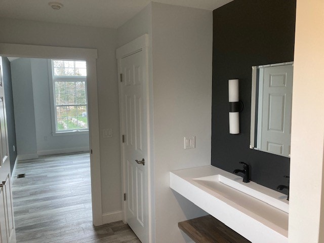 Wentworth New Build master bath with floating trough sink, dark accent wall, matte black sconce and faucet, and hallway view — Governor's Crossing, NH