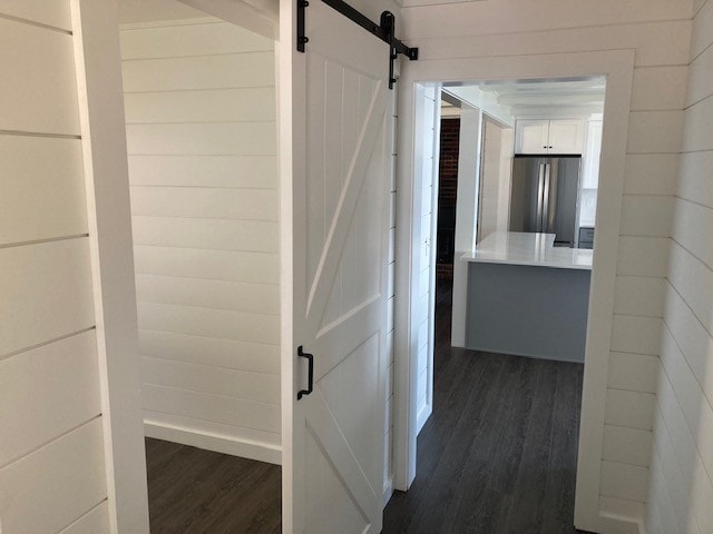Lake Winnisquam Cottage Remodel hallway with white shiplap walls, barn door, and view through to kitchen — Winnisquam, NH
