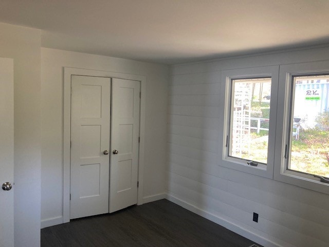 Lake Winnisquam Cottage Remodel bedroom with white shiplap walls, double closet doors, and two windows — Winnisquam, NH